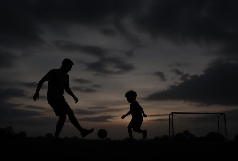 Silhouette of a father and young child playing at sunset